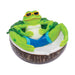 Green frog lounging in a coconut shell ashtray; deep white bowl with notch rests, angled view.