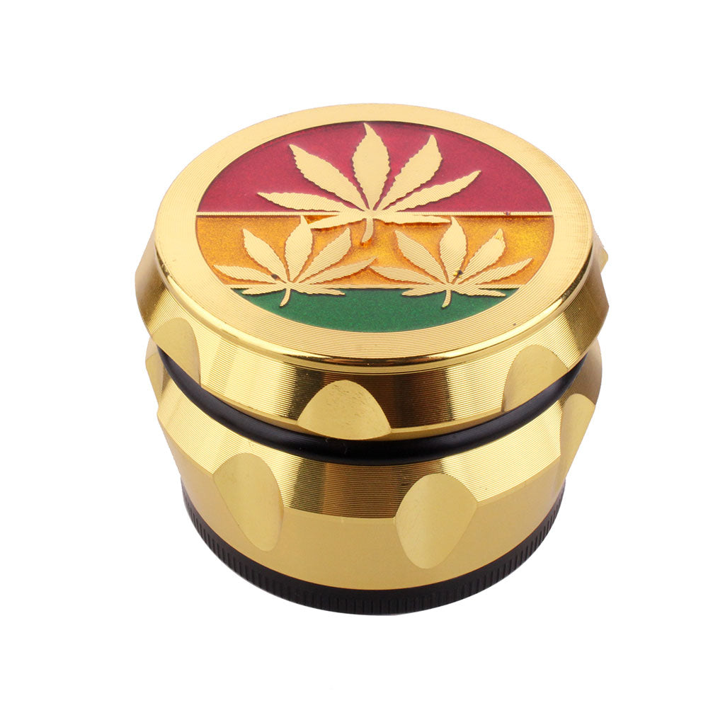 Angled view of vintage aluminum herb grinder with embossed 3 gold leaves design on rasta color lid