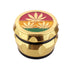 Angled view of vintage aluminum herb grinder with embossed 3 gold leaves design on rasta color lid